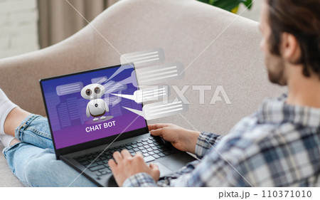 Unrecognizable man sitting on couch, using chatbot on laptop Unrecognizable man sitting on couch, using chatbot on laptop 110371010