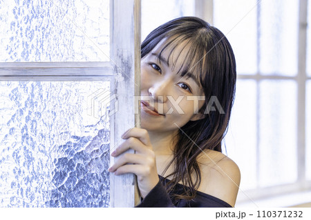 窓からのぞく黒ワンピースの若い女性 窓からのぞく黒ワンピースの若い女性 110371232