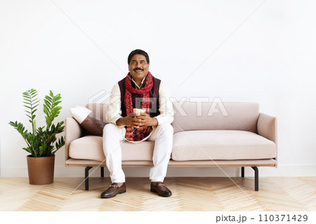 Happy hindu man enjoying morning coffee at home Happy hindu man enjoying morning coffee at home 110371429