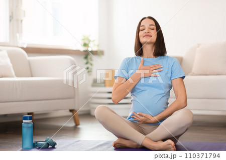 pregnant lady practicing yoga at home meditating focusing on breath 110371794
