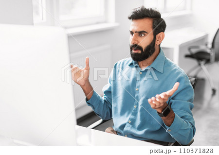 Surprised indian male office worker reacting to computer screen Surprised indian male office worker reacting to computer screen 110371828