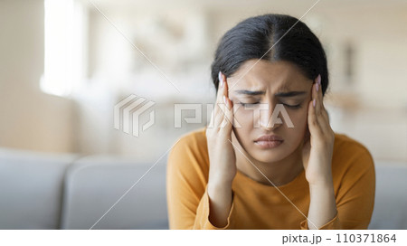 Stressed young indian woman suffering from severe headache or migraine at home Stressed young indian woman suffering from severe headache or migraine at home 110371864