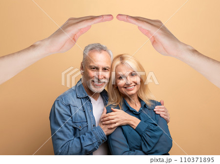 Happily married mature couple posing under roof on beige background Happily married mature couple posing under roof on beige background 110371895