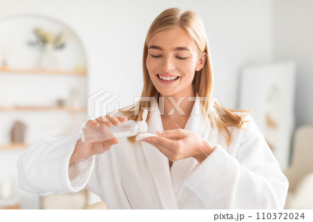 Young lady uses cotton pad and facial lotion in bathroom 110372024