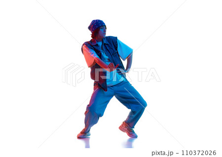 Dynamic image of young girl in casual sportive cloths dancing hip hop isolated over white background in neon light Dynamic image of young girl in casual sportive cloths dancing hip hop isolated over white background in neon light 110372026