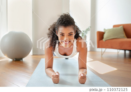 woman in activewear doing core strengthening plank exercise at home 110372125