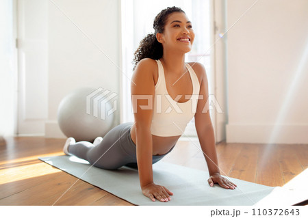 Fit woman in activewear practicing upward facing dog pose indoors 110372643