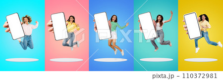Happy Millennial Women With Blank Smartphones In Hands Jumping Over Colorful Backgrounds 110372981