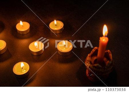 Many candles lit against a black background.Burning candles on dark tableMemory  110373038
