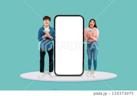 Teens with cash celebrating by large blank smartphone Teens with cash celebrating by large blank smartphone 110373075
