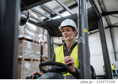 Female warehouse worker driving forklift. Warehouse worker preparing products for shipmennt, delivery, checking stock in warehouse. Female warehouse worker driving forklift. Warehouse worker preparing products for shipmennt, delivery, checking stock in warehouse. 110373188