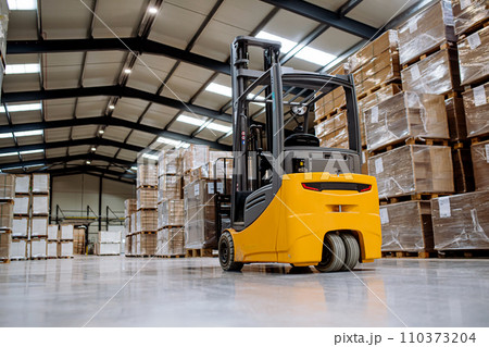 Back view of forklift in warehouse in the middle of stored goods.. Forklift driver preparing products for shipmennt, delivery, checking stock in warehouse. Back view of forklift in warehouse in the middle of stored goods.. Forklift driver preparing products for shipmennt, delivery, checking stock in warehouse. 110373204