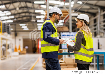 Female engineer and male project manager standing in modern industrial factory, talking about production. Team management in manufacturing facility Female engineer and male project manager standing in modern industrial factory, talking about production. Team management in manufacturing facility 110373288