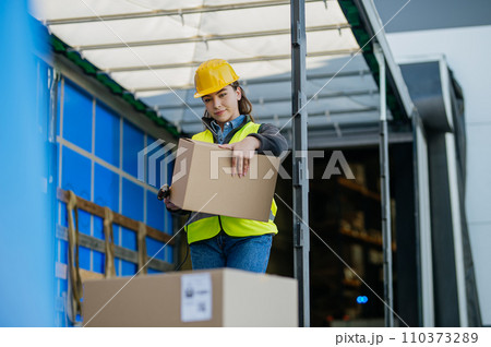 Warehouse receiver standing inside of truck in cargo area, trailer, barcode scanning delivered items. Receiving clerk holding scanner checking delivered goods against order. Warehouse receiver standing inside of truck in cargo area, trailer, barcode scanning delivered items. Receiving clerk holding scanner checking delivered goods against order. 110373289
