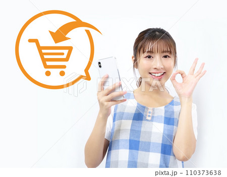 スマホのネットショッピングを利用するエプロン姿の若い女性イメージ スマホのネットショッピングを利用するエプロン姿の若い女性イメージ 110373638
