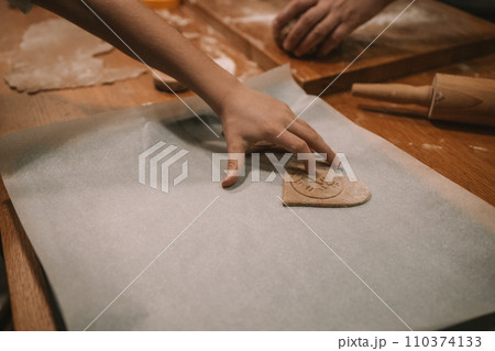 Process of making heart-shaped gingerbread for Christmas and New Year. Traditional festive food making, family culinary.  110374133