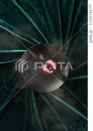 A halloween vampire teeth on plate with tableware on a Green Velvet Background 110374277