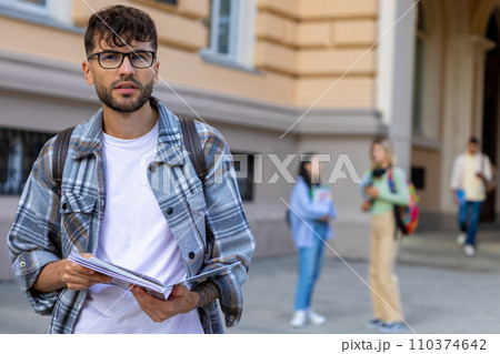 Young guy in eyeglasses and checkered shirt in the university yard 110374642