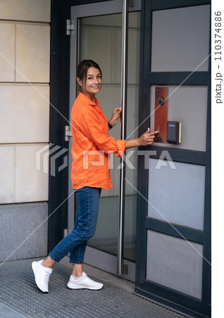 Brunette woman dialing an intercom to enter a building. Brunette woman dialing an intercom to enter a building. 110374886