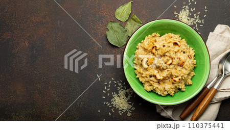 Ven Pongal (Khara Pongal), traditional Indian savoury rice dish made during celebrating Pongal festival, served in bowl top view on concrete rustic background, space for text Ven Pongal (Khara Pongal), traditional Indian savoury rice dish made during celebrating Pongal festival, served in bowl top view on concrete rustic background, space for text 110375441