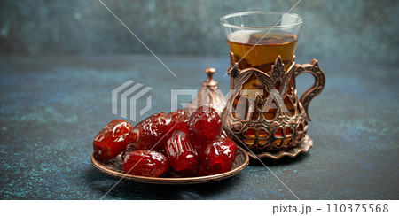 Breaking fasting with dried dates during Ramadan Kareem, Iftar meal with dates and Arab tea in traditional glass, angle view on rustic blue background. Muslim feast 110375568