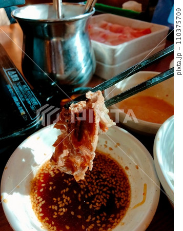 美味しい焼肉をたれにつけて食べる 美味しい焼肉をたれにつけて食べる 110375709