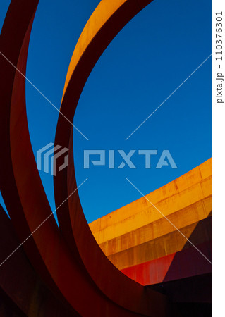 Abstract view of a modern sculptural architecture with vibrant red and yellow curves. Abstract view of a modern sculptural architecture with vibrant red and yellow curves. 110376301