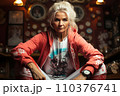 Portrait of a beautiful sporty senior woman in red jacket sitting in gym 110376741