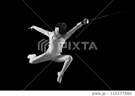 Artistry of combat. Female fencer gracefully executes complex fencing maneuver in action against black studio background. Concept of combat sport. Artistry of combat. Female fencer gracefully executes complex fencing maneuver in action against black studio background. Concept of combat sport. 110377980