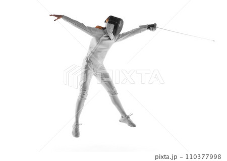 Skilled fencer executing graceful parry, concentration evident in her moves against neutral white studio background. Mental aspect of sport. 110377998