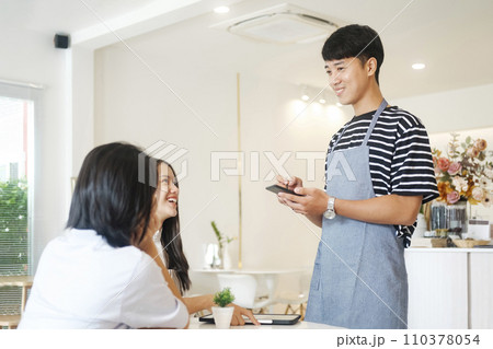 Smiling waiter take order talk to clients cafe restaurant visitors serving staff good customer service. 110378054