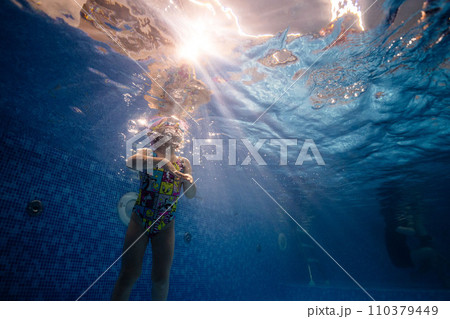 Little child swims underwater in swimming pool, happy active dives and has fun under water, kid fitness and sport  110379449