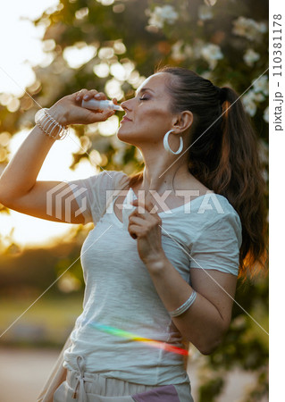 trendy woman in white shirt using nasal spray trendy woman in white shirt using nasal spray 110381178