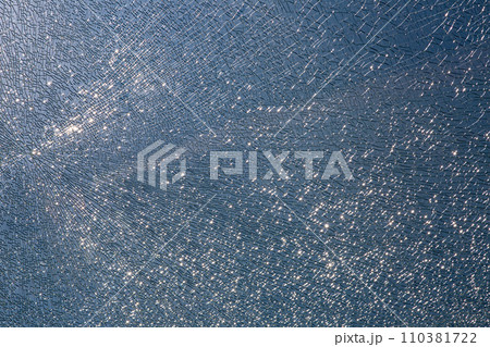 broken tempered glass in cracks, spoiled glass surface texture, close-up. broken tempered glass in cracks, spoiled glass surface texture, close-up. 110381722
