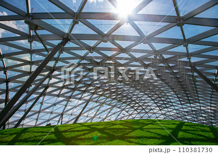 glass roof under the open sky with sun glare, indoor safety park with green hill lit by sunlight, nobody. 110381730