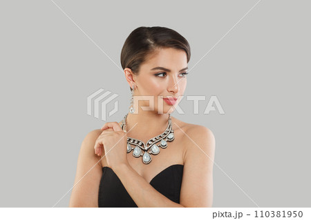 Cheerful jewelry model woman with dark brown hair and shiny fresh skin wearing diamond earring 110381950