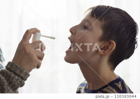 The child receives medication through a mouth spray for a sore throat The child receives medication through a mouth spray for a sore throat 110383044