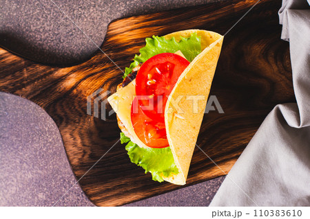 Close up of taco burger with cutlet, cheese and tomatoes on a board on the table top view 110383610