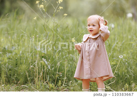 Child in field holding a flower. 110383667