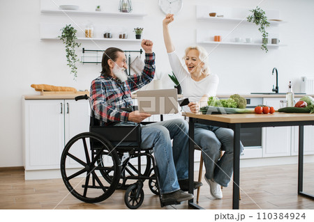 Caucasian couple, pretty wife and bearded man in wheelchair, pay for food with credit card. Caucasian couple, pretty wife and bearded man in wheelchair, pay for food with credit card. 110384924