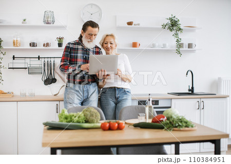 Elderly husband and wife searching internet for recipe for healthy breakfast. Elderly husband and wife searching internet for recipe for healthy breakfast. 110384951