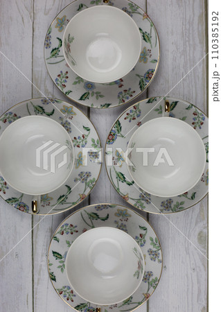 Top view of a porcelain tea set with flowers on a white table. Utensils for preparing hot drinks Top view of a porcelain tea set with flowers on a white table. Utensils for preparing hot drinks 110385192