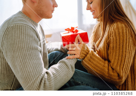 Valentine's Day concept. Exchange of gifts. Young couple at home celebrating Valentine's Day. 110385268