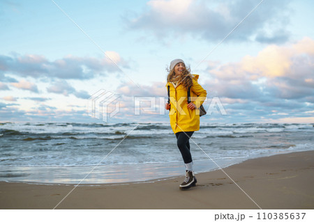 The girl tourist in a yellow jacket posing by the sea. Travelling, lifestyle, adventure. 110385637