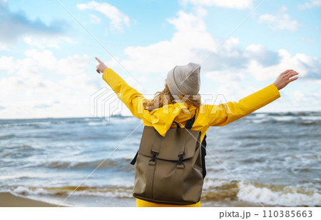 The girl tourist in a yellow jacket posing by the sea. Travelling, lifestyle, adventure. The girl tourist in a yellow jacket posing by the sea. Travelling, lifestyle, adventure. 110385663