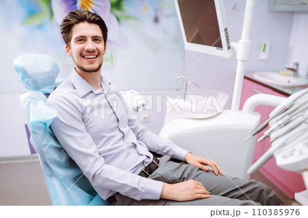 Young man at the dentist's chair during a dental procedure. Overview of dental caries prevention. 110385976