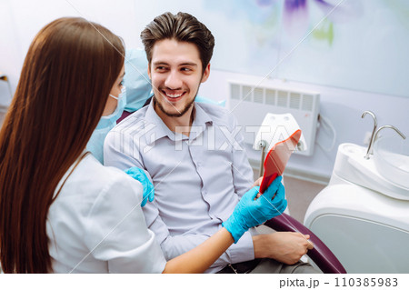 Young man at the dentist's chair during a dental procedure. Overview of dental caries prevention. 110385983