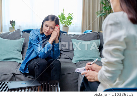 Sad young woman at therapy session with psychologist Sad young woman at therapy session with psychologist 110386315