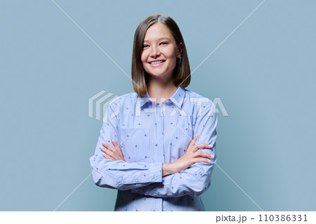 Portrait of confident young woman with crossed arms on blue background 110386331
