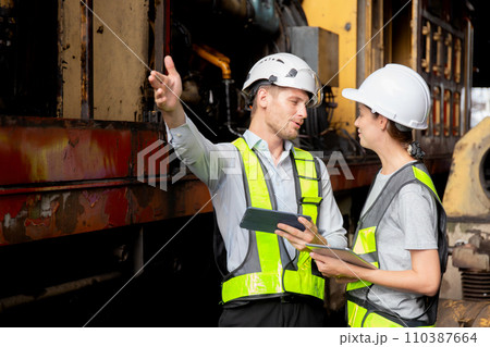 Young caucasian engineer man and woman checking train with tablet in station. Young caucasian engineer man and woman checking train with tablet in station. 110387664